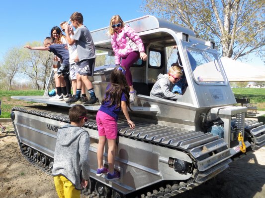 Kids climbing around a small amphibious vehicle