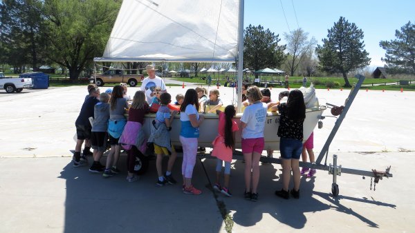 Kids standing around a sailboat.