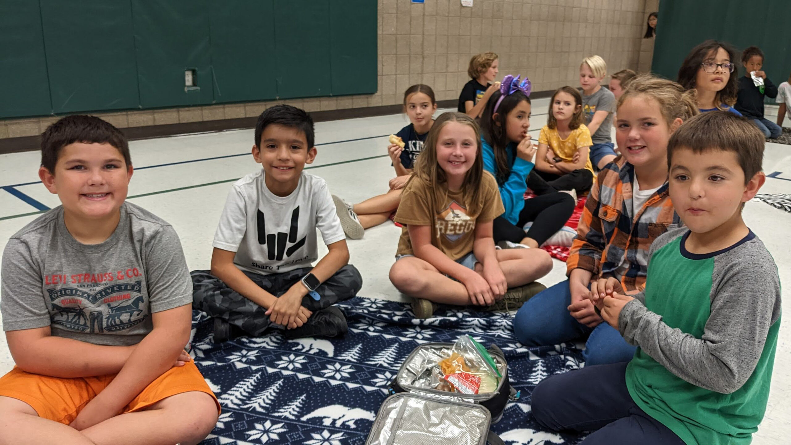 Children enjoying lunch on a blanket.