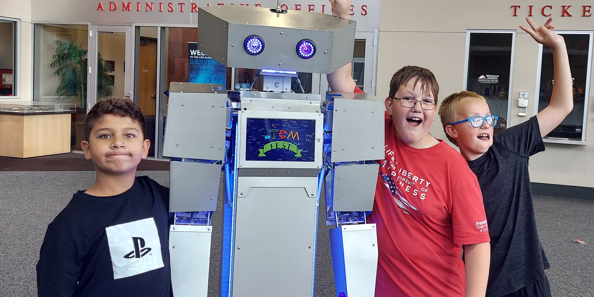 Students standing with robot greeter.