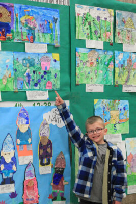 Student pointing out his artwork.