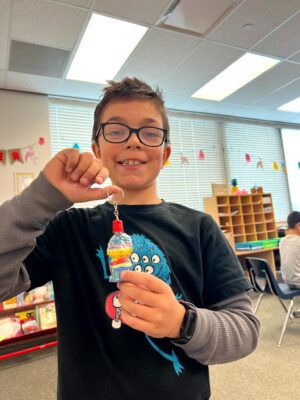 Student creating a sand filled necklace.