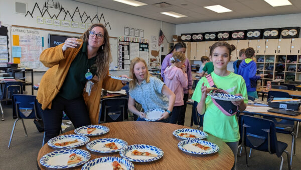 Teacher and students eating pizza.