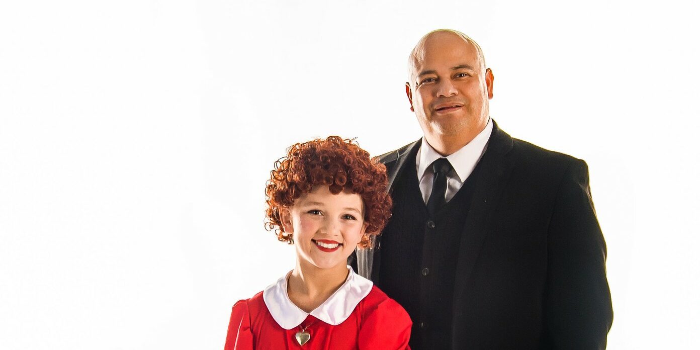 Young girl dressed as Annie and man playing Daddy Warbucks.
