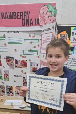 Young boy with STEM Fair award.