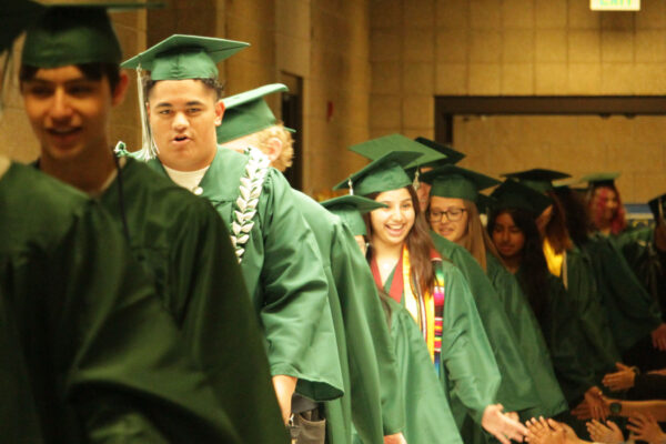 Graduates in caps and gowns greeting students as they progress around the school.