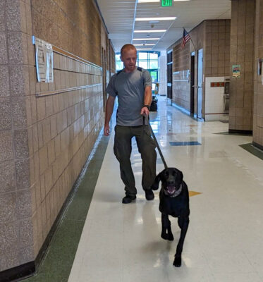 Handler leading dog through halls.