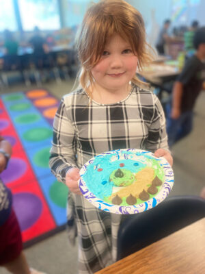 Young girl with relief map created with icing and other edible treats on a paper plate.