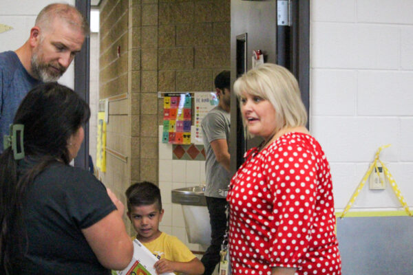 Teacher welcomes a young student and their parents.