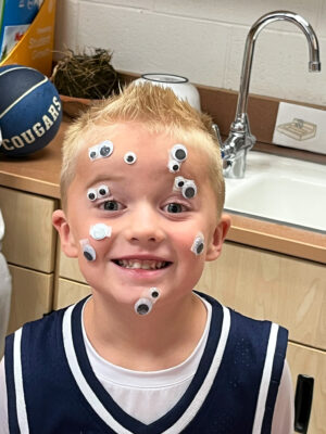 Young boy with googily eyes on his face.