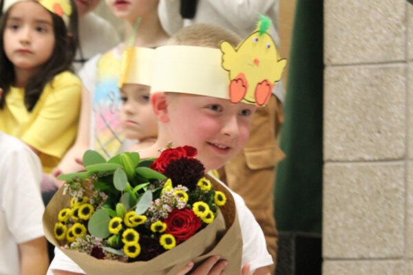 Young boy dressed as chick presenting flowers to pianist.