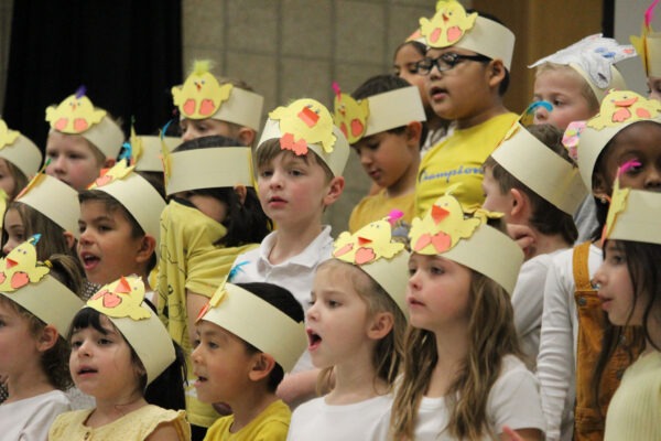 Kindergarten children in yellow and white singing.