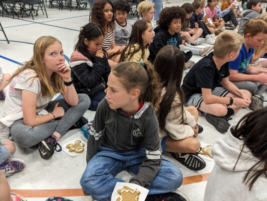 Students eating cookies and listening to a book.