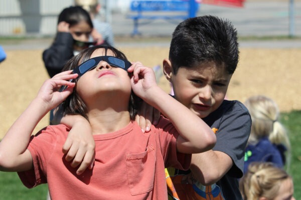 Two boys taking turns watching the eclipse.