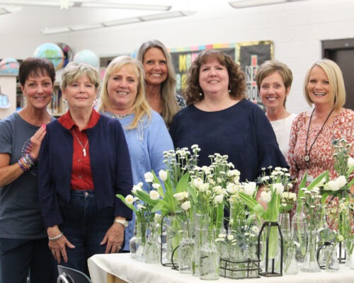 A group of former teachers posed with flowers.