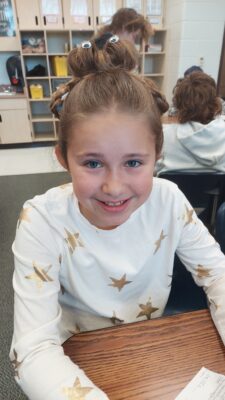 girl student at her desk smiling at the camera